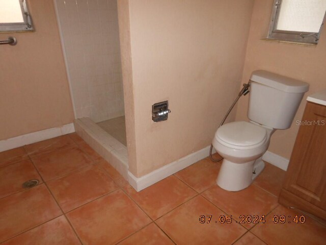 bathroom featuring tile patterned flooring, baseboards, tiled shower, and toilet