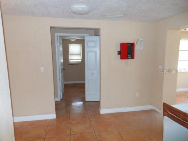 empty room with light tile patterned floors, baseboards, and a textured ceiling