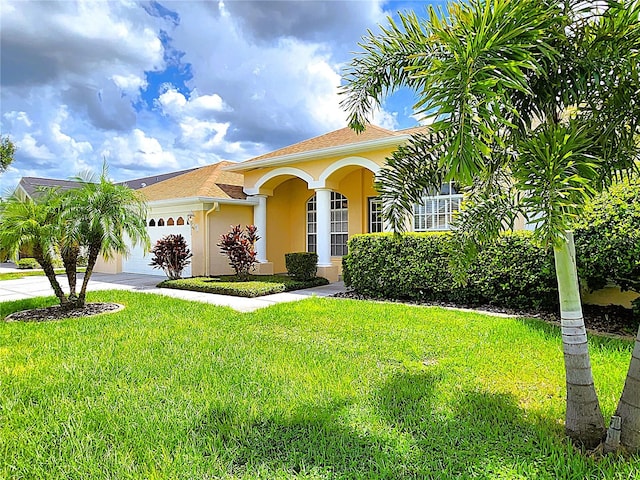 mediterranean / spanish-style home with stucco siding, driveway, a front yard, and a garage