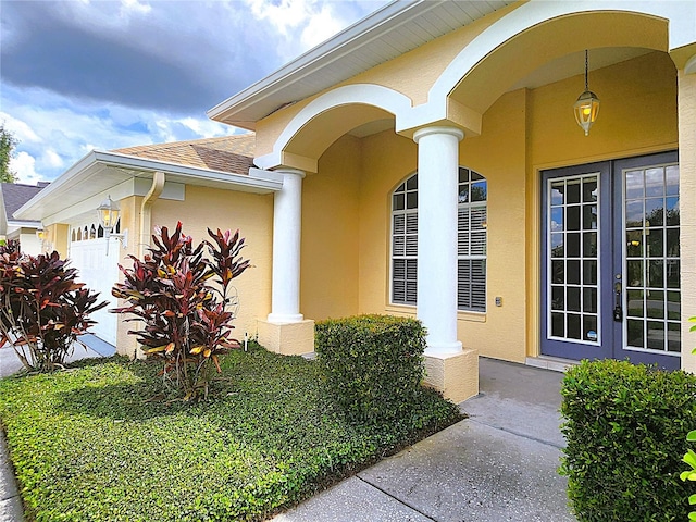 property entrance featuring a shingled roof, french doors, a garage, and stucco siding