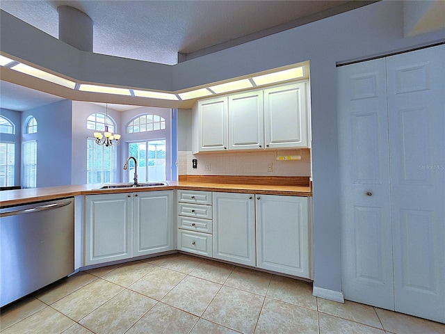 kitchen with a sink, backsplash, stainless steel dishwasher, white cabinets, and a chandelier