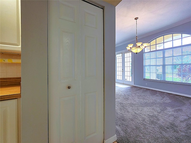 hallway featuring baseboards, carpet floors, a notable chandelier, and crown molding