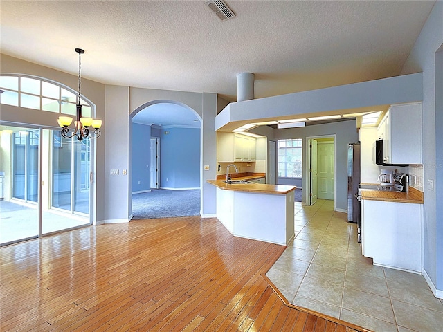 kitchen featuring pendant lighting, white cabinets, sink, a notable chandelier, and kitchen peninsula