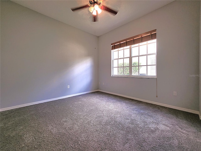 empty room with a ceiling fan, baseboards, and dark carpet