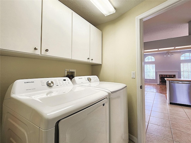 laundry room with cabinets, washer and dryer, ceiling fan, light tile patterned floors, and a fireplace