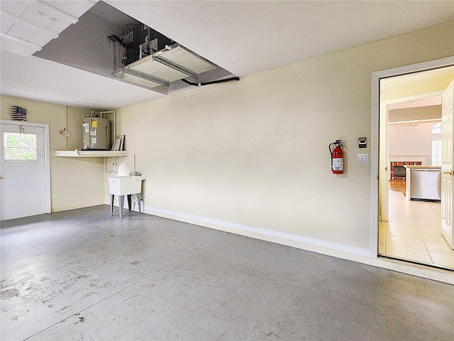 garage with water heater, baseboards, and a sink