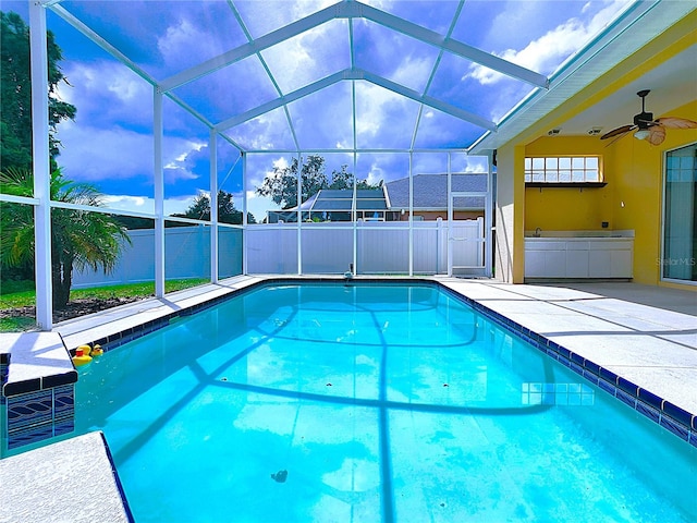 view of pool featuring a fenced in pool, ceiling fan, fence, a lanai, and a patio