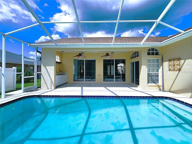 view of swimming pool with glass enclosure, ceiling fan, and a patio