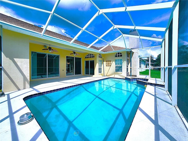 view of pool featuring glass enclosure, ceiling fan, a patio, and a jacuzzi