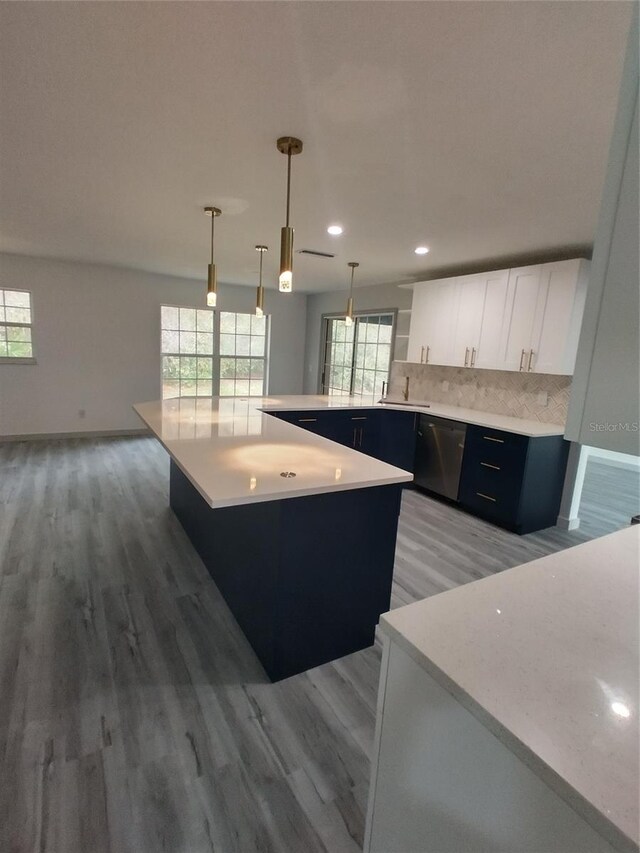 kitchen with a kitchen island, hardwood / wood-style floors, pendant lighting, tasteful backsplash, and white cabinetry