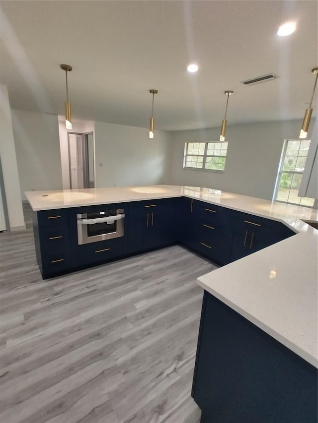 kitchen with hanging light fixtures, stainless steel oven, and kitchen peninsula