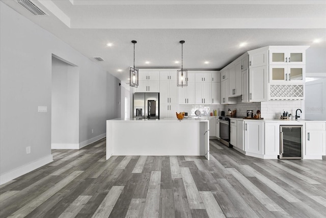 kitchen with appliances with stainless steel finishes, beverage cooler, and white cabinets