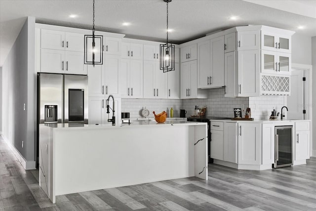 kitchen featuring white cabinets, stainless steel refrigerator with ice dispenser, pendant lighting, and beverage cooler