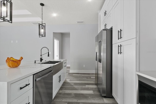 kitchen featuring pendant lighting, sink, white cabinetry, stainless steel appliances, and dark hardwood / wood-style floors