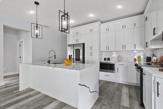 kitchen featuring built in microwave, white cabinetry, an island with sink, electric range, and stainless steel fridge with ice dispenser