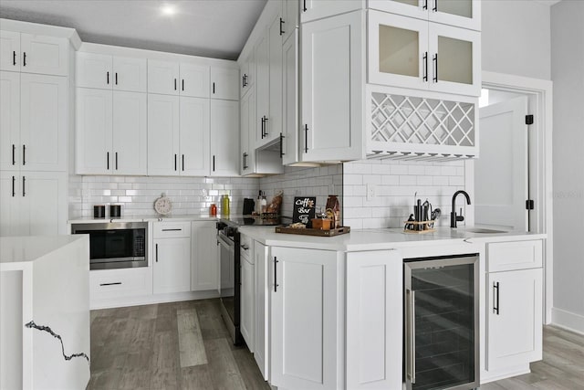 kitchen featuring stainless steel microwave, sink, white cabinets, beverage cooler, and electric stove