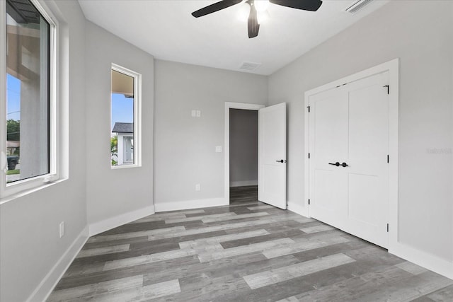 unfurnished bedroom featuring ceiling fan, a closet, and light wood-type flooring