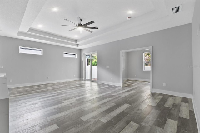 unfurnished room with wood-type flooring, ceiling fan, and a tray ceiling