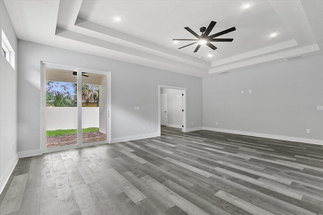 empty room featuring hardwood / wood-style floors, ceiling fan, and a tray ceiling