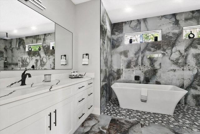 bathroom featuring vanity, a wealth of natural light, tile walls, and a bathing tub