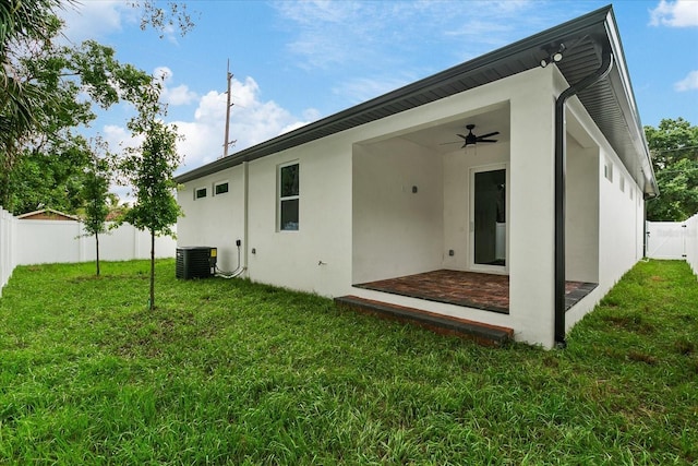 rear view of house with ceiling fan, a yard, and central air condition unit