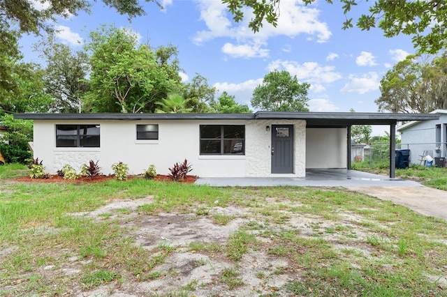 view of front of property with a front yard, an attached carport, concrete driveway, and stucco siding