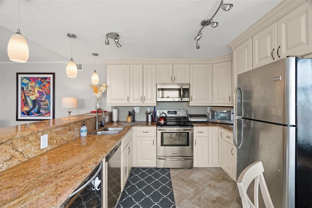 kitchen featuring pendant lighting, sink, a textured ceiling, appliances with stainless steel finishes, and light stone counters