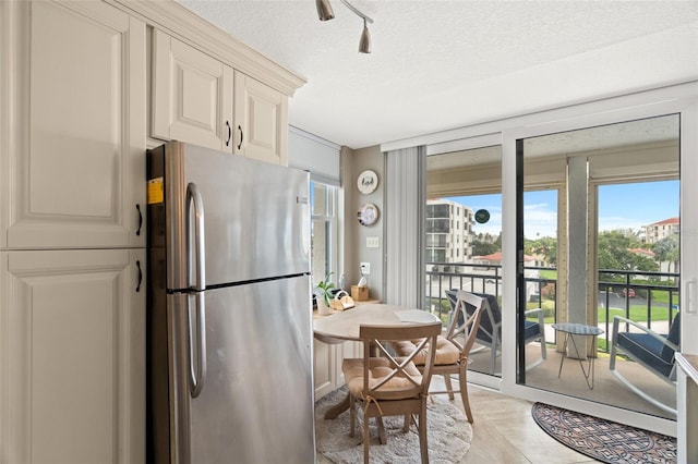 kitchen featuring stainless steel fridge, light tile patterned floors, and a textured ceiling