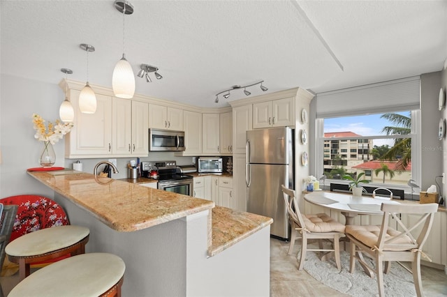 kitchen featuring a breakfast bar, hanging light fixtures, appliances with stainless steel finishes, light stone counters, and kitchen peninsula