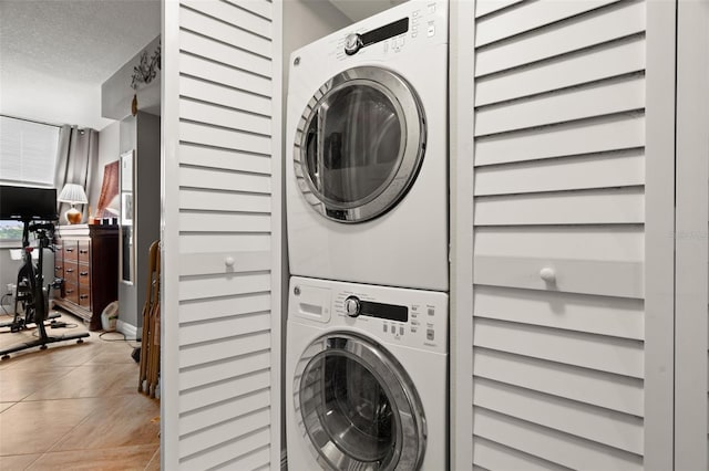 washroom featuring stacked washer / dryer, light tile patterned floors, and a textured ceiling