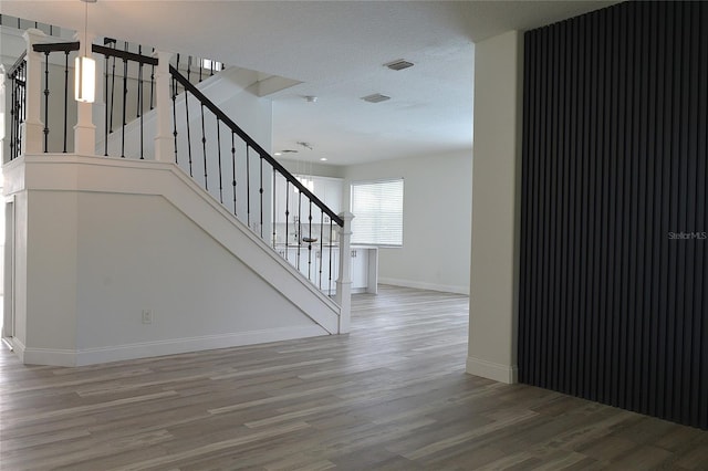 stairway featuring a textured ceiling and hardwood / wood-style floors