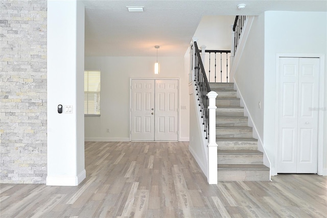 entryway with light wood-type flooring and a textured ceiling