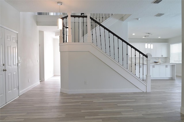 stairway featuring light hardwood / wood-style floors and a textured ceiling