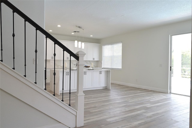 stairs featuring light hardwood / wood-style flooring and a textured ceiling