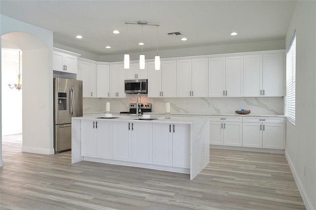 5308 Cedarshake Ln, Valrico, FL 33596 - kitchen with white cabinets, stainless steel appliances, light countertops, arched walkways, and decorative backsplash