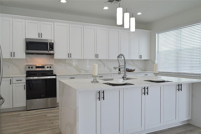 5308 Cedarshake Ln, Valrico, FL 33596 - kitchen featuring white cabinets, a sink, light wood-type flooring, hanging light fixtures, and appliances with stainless steel finishes