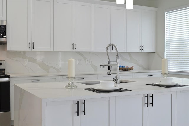 kitchen with white cabinetry, decorative backsplash, sink, light stone countertops, and appliances with stainless steel finishes