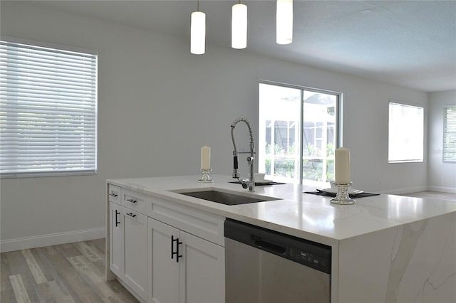 kitchen featuring light hardwood / wood-style flooring, a kitchen island with sink, stainless steel dishwasher, light stone countertops, and sink