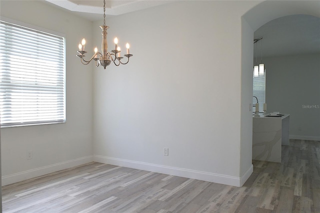 5308 Cedarshake Ln, Valrico, FL 33596 - spare room with arched walkways, a healthy amount of sunlight, a chandelier, and light wood-type flooring