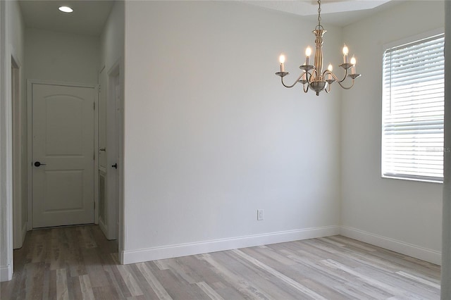 spare room with a chandelier and hardwood / wood-style floors