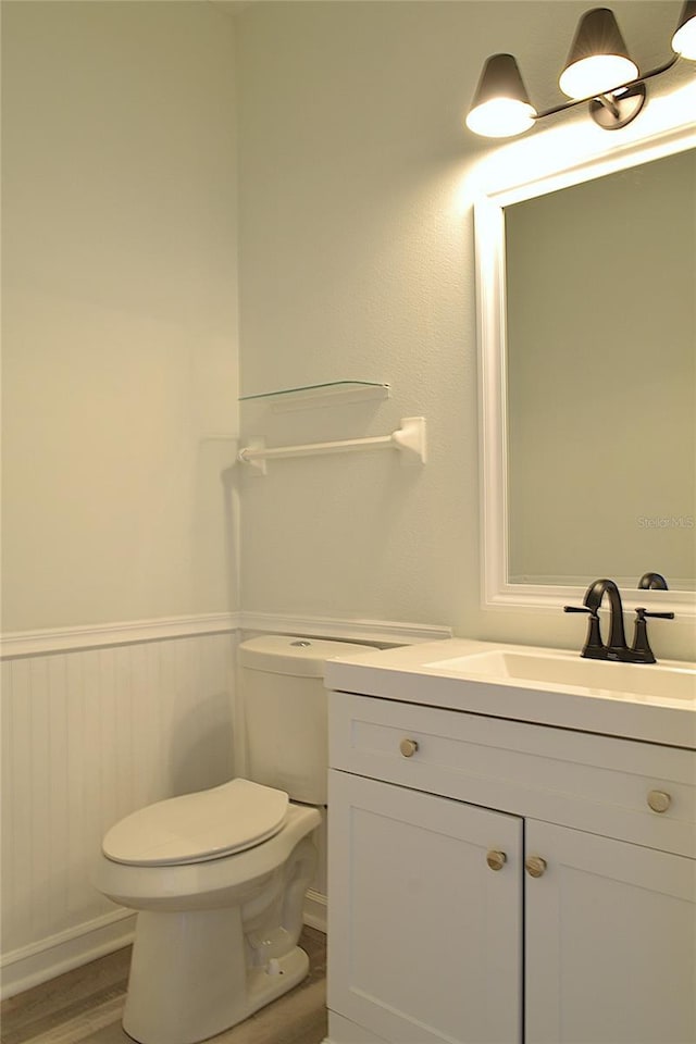 5308 Cedarshake Ln, Valrico, FL 33596 - bathroom featuring toilet, vanity, wood finished floors, and a wainscoted wall