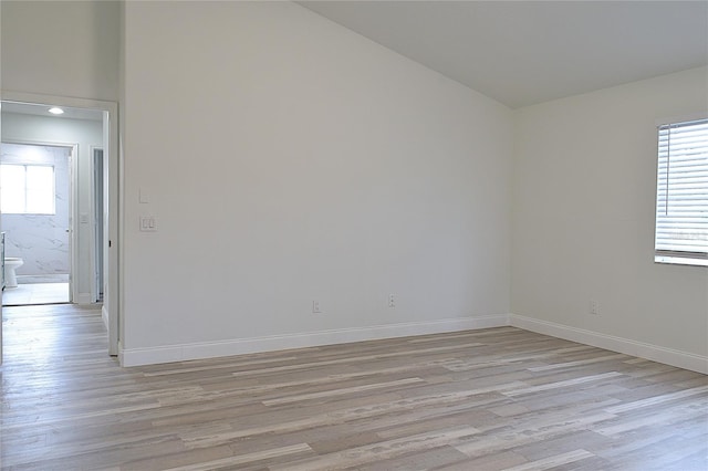 empty room with light hardwood / wood-style floors and high vaulted ceiling