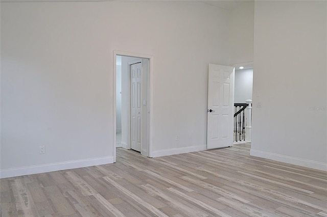 empty room with light hardwood / wood-style flooring and a towering ceiling