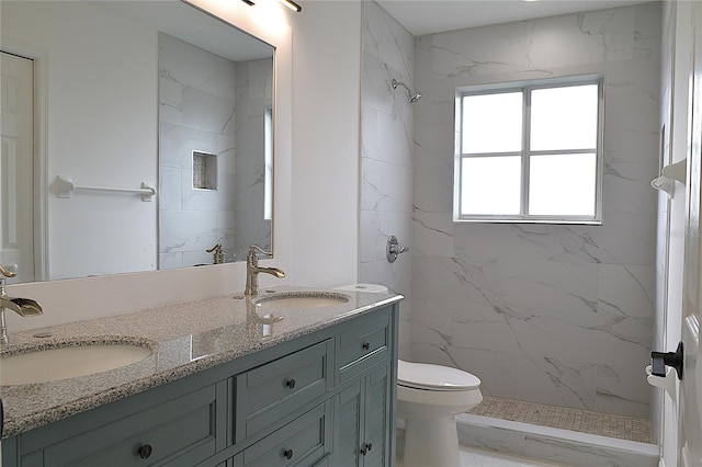 bathroom featuring double vanity, toilet, and tiled shower