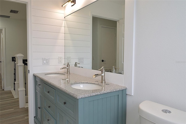 bathroom with wood-type flooring, toilet, and double sink vanity