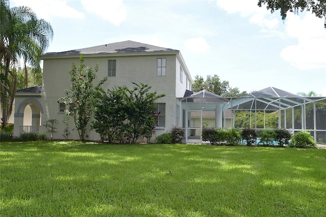 rear view of property with a lawn and glass enclosure