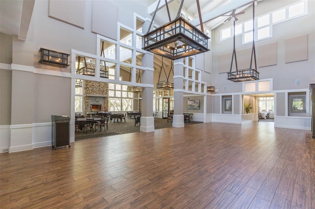 unfurnished living room with wood-type flooring, ceiling fan, and a towering ceiling