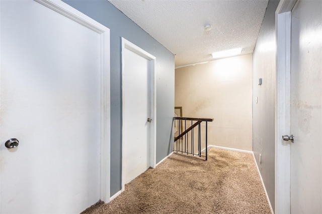 hallway featuring carpet flooring and a textured ceiling