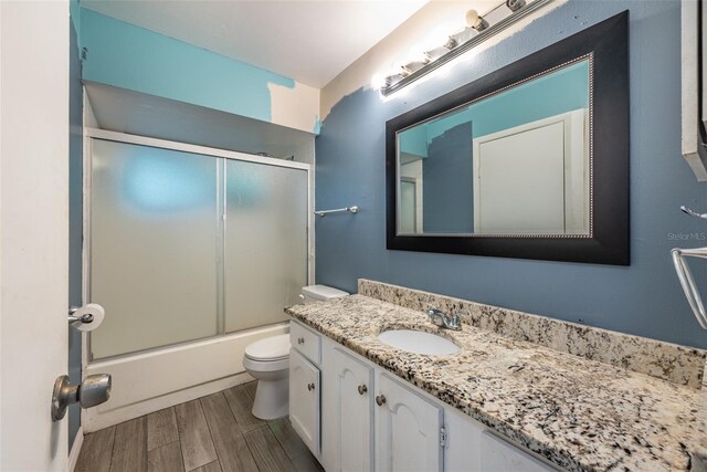 full bathroom with vanity, toilet, combined bath / shower with glass door, and hardwood / wood-style floors