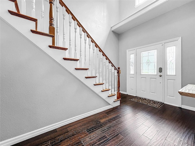 entryway featuring a towering ceiling and dark wood-type flooring